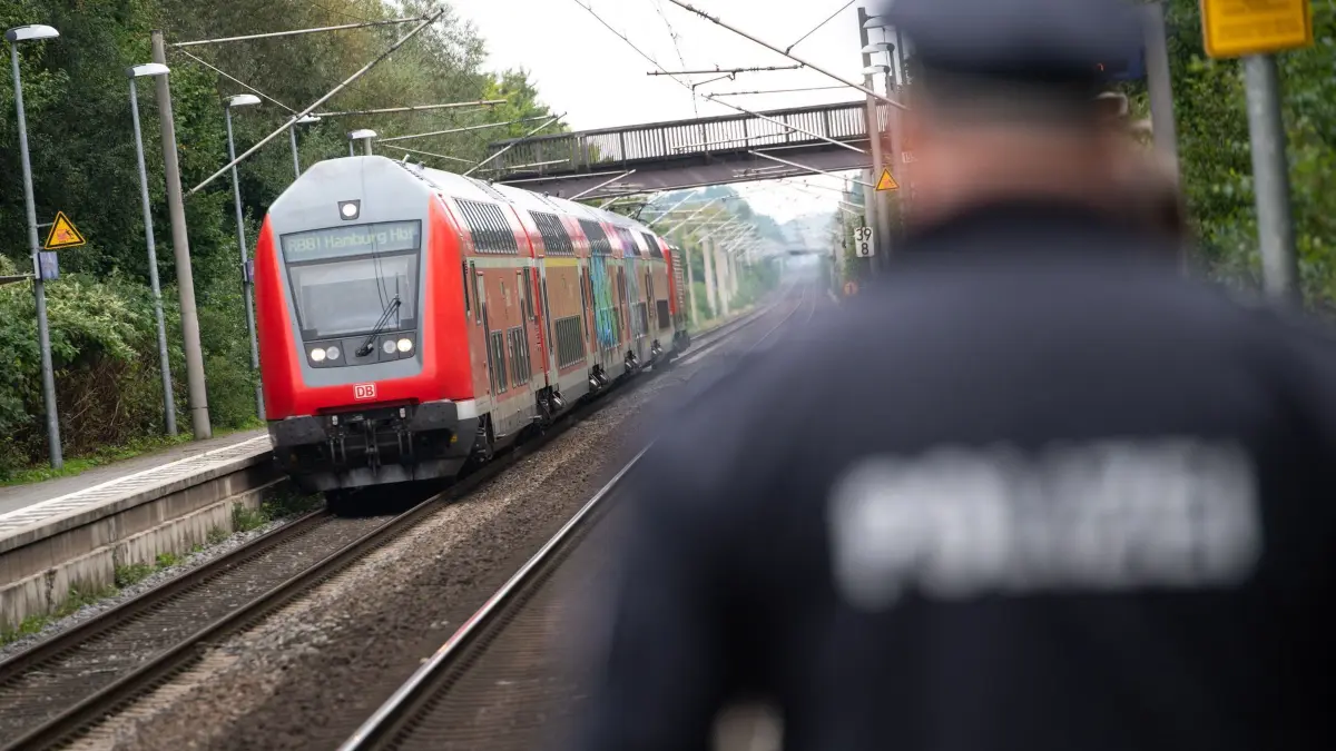 Zugbegleiter angegriffen: ARCHIV - 16.09.2021, Schleswig-Holstein, Ahrensburg: Ein Polizist läuft über einen Bahnsteig während im Hintergrund ein doppelstöckiger Regionalzug der Deutschen Bahn (DB) in den Bahnhof einfährt. (zu dpa: «Zugbegleiter bespuckt und angegriffen») Foto: Jonas Walzberg/dpa +++ dpa-Bildfunk +++