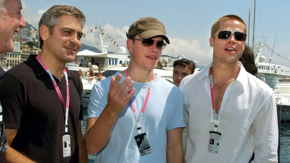 Die Hollywood-Stars George Clooney, Brad Pitt und Matt Damon (v.l.) posieren am Samstag (22.05.2003) vor der Hafenkulisse von Monaco. Die Stars machen Werbung für ihren neuen Film "Oceans Twelve", das Jaguar Team hat das Logo und den Schriftzug des Filmes auf ihren Rennwagen. Am Sonntag startet hier der Große Preis von Monaco. Foto: Oliver Multhaup dpa +++ dpa-Bildfunk +++