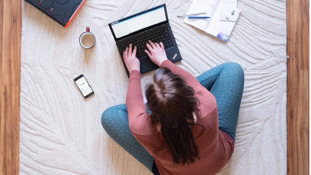 PRODUKTION - 02.03.2022, Sachsen, Dresden: Eine Frau sitzt im Homeoffice auf einem Teppich und arbeitet an einem Laptop (gestellte Szene). Das Ende der Homeoffice-Pflicht am vergangenen Sonntag hat keine größeren Auswirkungen im Berufsverkehr. (zu dpa «Ende der Homeoffice-Pflicht: Kein Stauanstieg im Berufsverkehr») Foto: Sebastian Kahnert/dpa-Zentralbild/dpa +++ dpa-Bildfunk +++