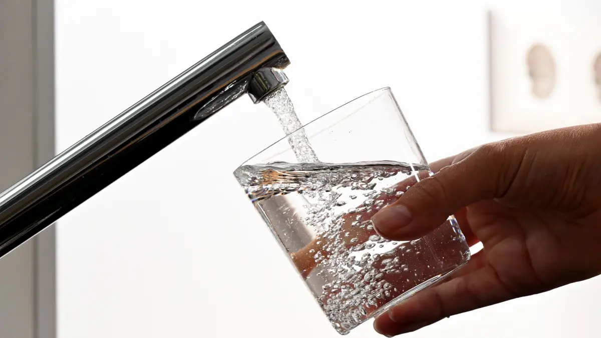 ILLUSTRATION - Eine Hand hält ein Wasserglas unter einen Wasserhahn. (zu dpa: "Keime in Bretzfelder Trinkwasser entdeckt - Abkochgebot") +++ dpa-Bildfunk +++