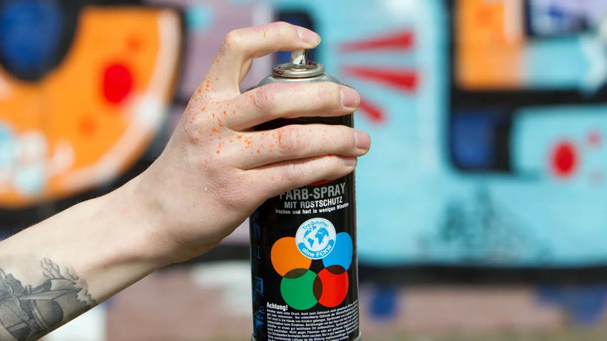ILLUSTRATION - Eine Spraydose wird am Freitag (16.04.2010) in Münster vor eine Wand mit Graffitis gehalten. Knapp 30 Jahre nach der Graffiti-Welle aus den USA wird weiter gesprüht und gemalt - gern auf fremdem Hab und Gut. Nahezu täglich melden die Polizeidienststellen Sprühattacken auf Züge, Bahnhöfe, Haltetellen, Hausfassaden oder Parkbänke. Foto: Friso Gentsch dpa/lnw (zu dpa/lnw-KORR: "Graffiti-Sprayer treiben es noch immer bunt" vom 25.04.2010) +++(c) dpa - Bildfunk+++