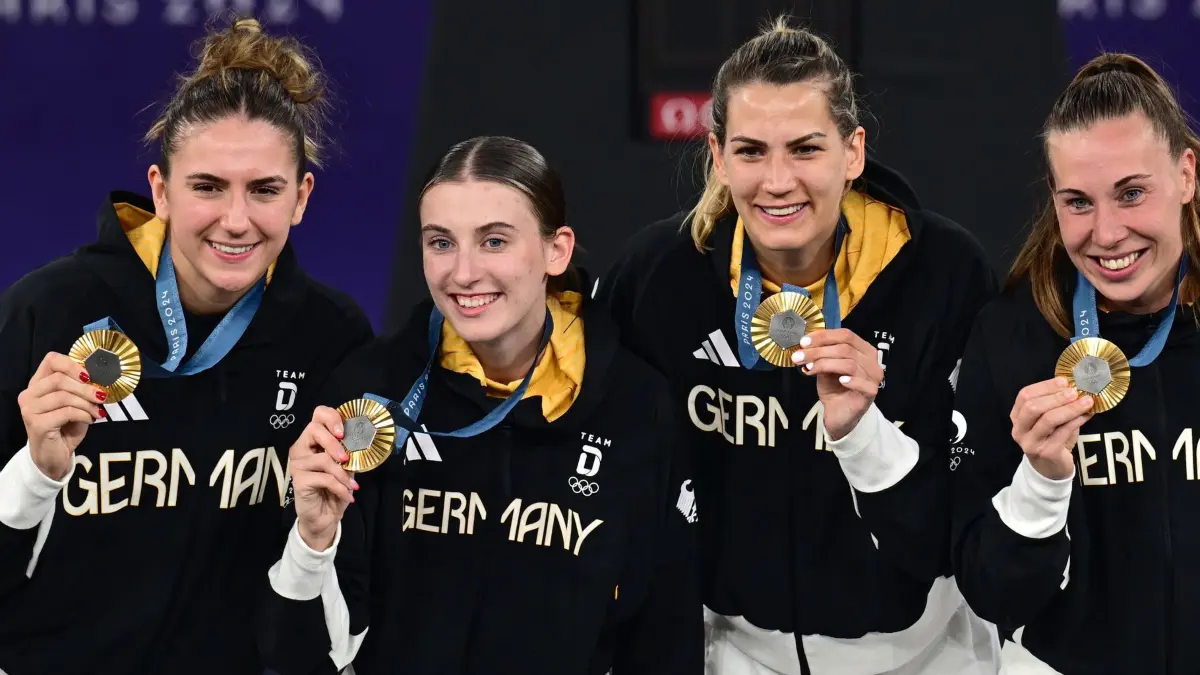 Paris 2024 - Basketball 3x3: 06.08.2024, Frankreich, Paris: Olympia, Paris 2024, 3x3 Basketball, Damen, Finale, Deutschland - Spanien, Finalrunde, Place de la Concorde, Deutschlands Marie Reichert (l-r), Elisa Mevius, Sonja Greinacher und Svenja Brunckhorst jubeln bei der Siegerehrung. Foto: Sina Schuldt/dpa +++ dpa-Bildfunk +++