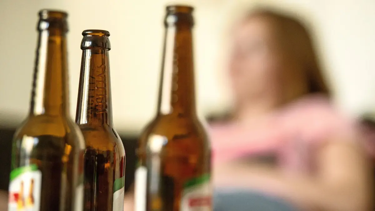 ILLUSTRATION - 28.05.2016, Berlin: Eine junge Frau sitzt hinter leeren Bierflaschen. (zu dpa: «Drogenberatung: Alkohol immer seltener das einzige Problem» vom 16.06.2018) Foto: Alexander Heinl/dpa +++ dpa-Bildfunk +++
