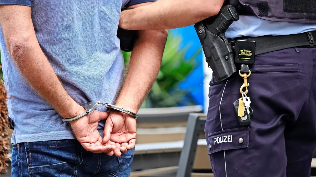 30.07.2019, Nordrhein-Westfalen, Essen: Ein Mann steht in Handschellen neben einem Polizisten. Bei einer Schlägerei im Clan-Milieu zwischen zwei polizeibekannten Clanfamilien ist ein Mann leicht verletzt worden. Foto: Johannes Neudecker/dpa +++ dpa-Bildfunk +++ | Verwendung weltweit