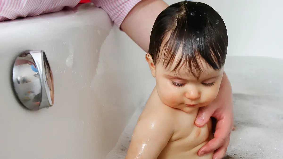 Ein Kleinkind wird gebadet: ILLUSTRATION - Kleine Kinder immer im Auge behalten: Doch sind beim Planschen kleine Mengen verschlucktes Wasser unbedenklich. (zu dpa: «Lebensgefahr? Wenn das Kind beim Planschen Wasser schluckt») Foto: Mascha Brichta/dpa-mag - ACHTUNG: Nur zur redaktionellen Verwendung im Zusammenhang mit dem genannten Text - Honorarfrei nur für Bezieher des Dienstes dpa-Magazin +++ dpa-Magazin +++