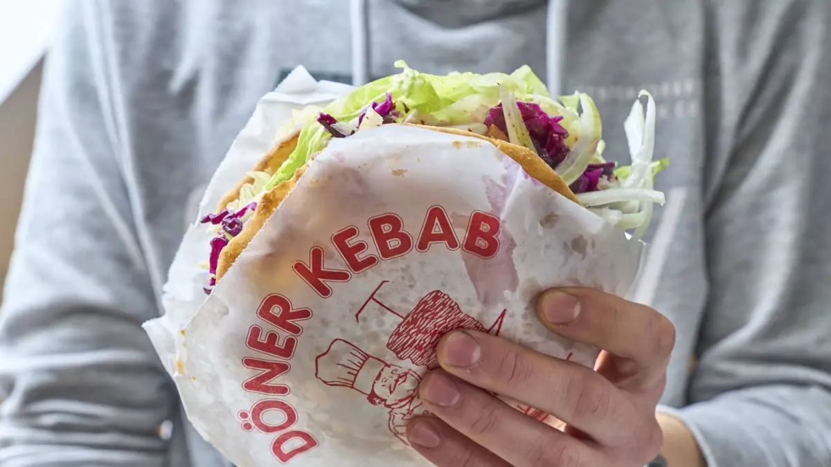 Augsburg, Bayern, Deutschland - 21 März 2024: Mann hält einen türkischen Döner Kebap in der Hand *** Man holding a Turkish doner kebab