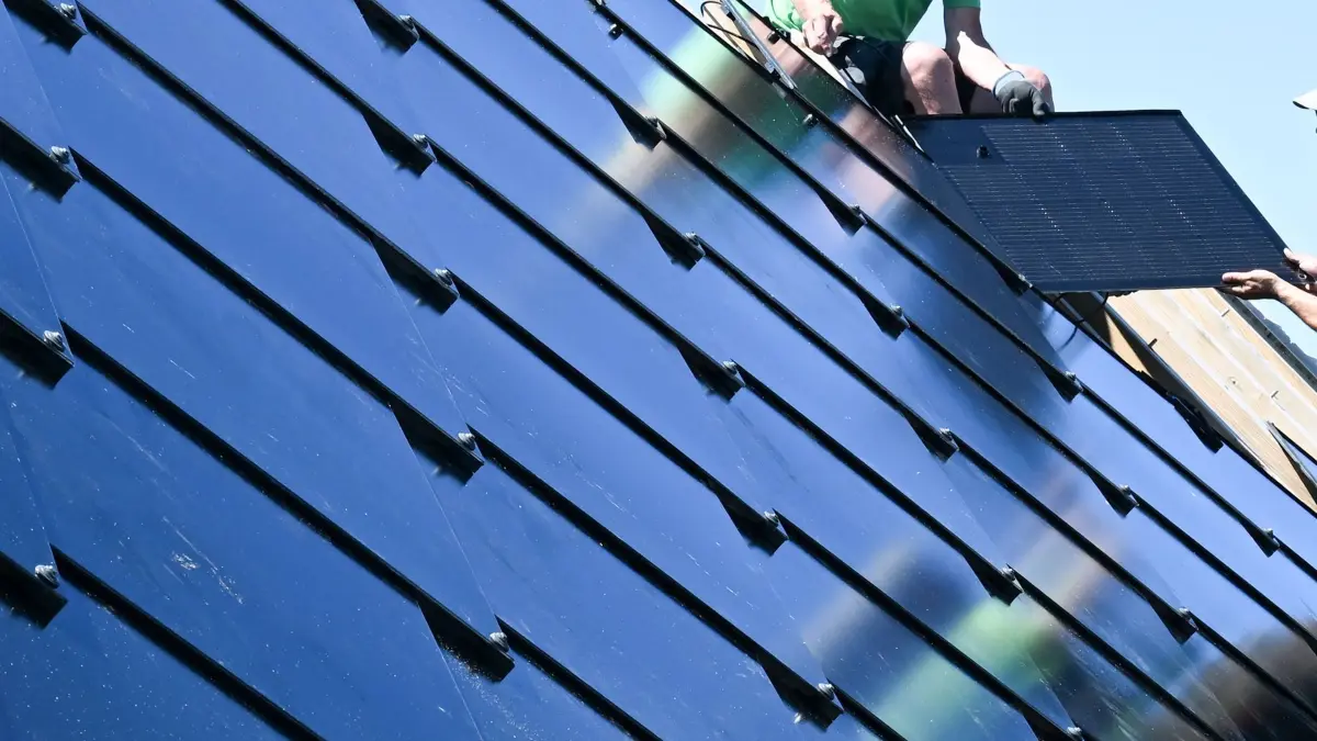 ARCHIV - 09.07.2024, Baden-Württemberg, Leinfelden-Echterdingen: Handwerker arbeiten an einem Photovoltaik Dach. Die neuartige PV Anlage besteht aus Photovoltaik Modulen in Form von Dachplatten. (zu dpa: «Zubau mit Solarenergie im Südwesten geht voran») Foto: Bernd Weißbrod/dpa +++ dpa-Bildfunk +++
