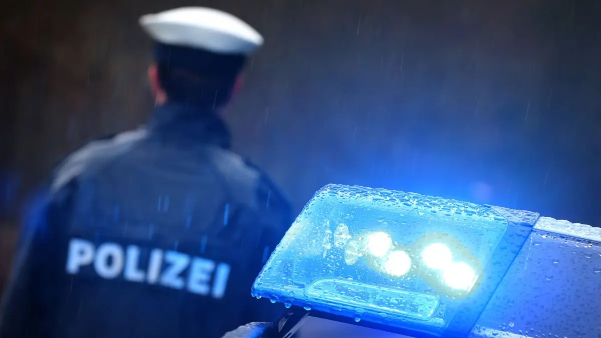ARCHIV - 15.03.2019, Bayern, Kempten: ILLUSTRATION - Ein Polizist steht im Regen vor einem Streifenwagen dessen Blaulicht aktiviert ist. Eine junge Frau soll einen vier Jahre alten Bub in Eschenbach in der Oberpfalz mit Gewalt getötet haben. Sie sitze wegen des Verdachts des Totschlags in Untersuchungshaft, teilte die Polizei am Freitag mit. Foto: Karl-Josef Hildenbrand/dpa +++ dpa-Bildfunk +++