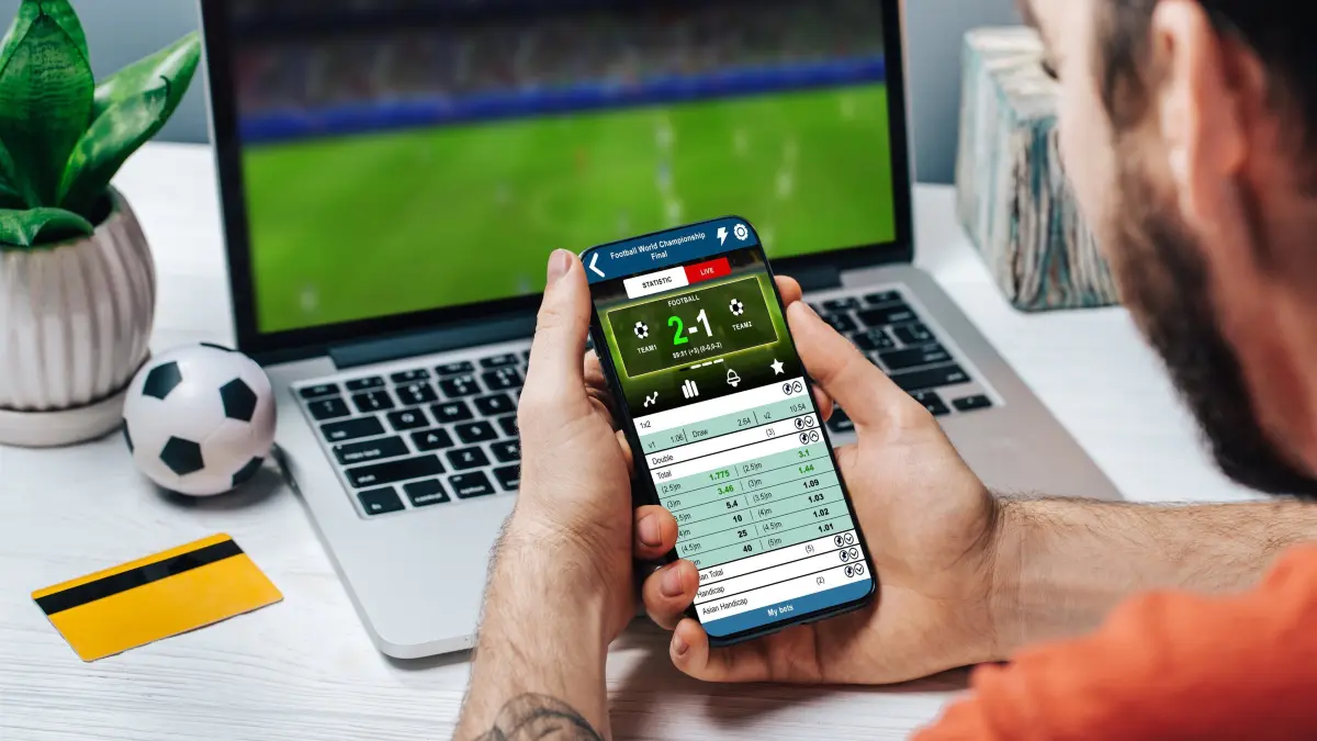 BEACHTEN: NPG-Standardlizenz: Sportwetten, Spielsucht, Mann mit Handy und Labtop. Download am 20.9.22 für Redaktion Reutlingen. Foto: © wpadington/adobe.stock.com