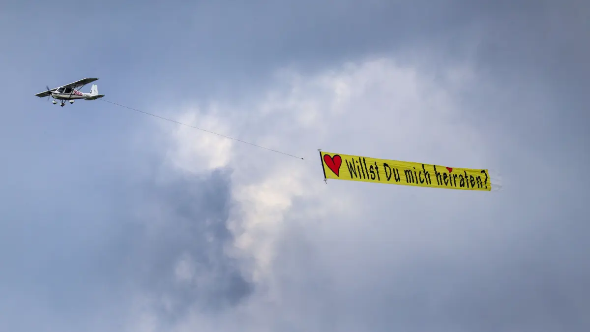 Ein Ultraleichtflugzeug zieht ein Banner mit der Aufschrift: «Willst Du mich heiraten?» hinter sich her. +++ dpa-Bildfunk +++