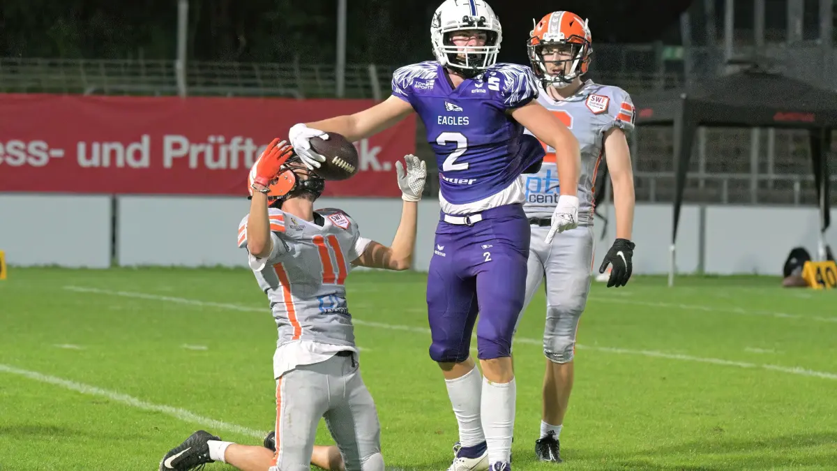 American Football RL | SSV Reutlingen 05 Eagles vs. Fellbach Warriors: American Football | SSV Reutlingen 05 Eagles (lila) vs. Fellbach Warriors (grau) // 2024-08-31 // Foto: Joachim Baur // #2 Carl Otto Sigloch (SSV Reutlingen Eagles) gestoppt von #11 Yeray Andreu Gonzalez Martinez (Warriors), li / #6 Lars Paul Kanthak (Warriors)