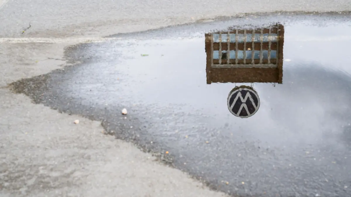 Volkswagen AG: ARCHIV - 29.05.2024, Niedersachsen, Wolfsburg: Das Markenhochhaus auf dem Gelände vom VW Werk Wolfsburg spiegelt sich in einer Pfütze. Die Volkswagen AG lädt seine Aktionäre zur ordentlichen Hauptversammlung. (zu dpa: «VW will sparen: Werksschließungen und Entlassungen drohen») Foto: Julian Stratenschulte/dpa +++ dpa-Bildfunk +++