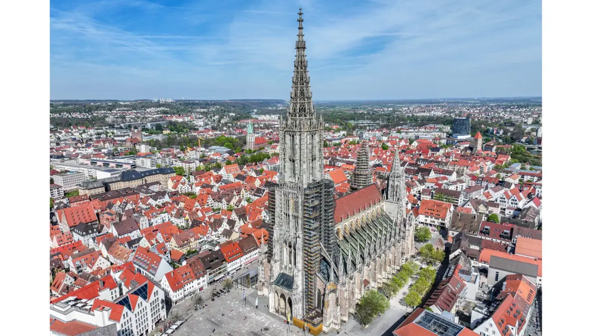 PRODUKTION - 12.04.2024, Baden-Württemberg, Ulm: Das Münster (Aufnahme mit Drohne). Das Ulmer Münster kämpft mit bröckelndem Putz, Schimmel, Rissen und dem Klimawandel. Ein neues Projekt mit Datenloggern und einer KI soll dem Jahrhunderte alten Gebäude nun helfen, sich mitzuteilen. Die Kirche mit dem höchsten Kirchturm der Welt leidet unter ihrem Alter und dem Klimawandel. (zu dpa: «Moderne Technik für ein altes Gebäude - KI soll Ulmer Münster sichern») Foto: Jason Tschepljakow/dpa +++ dpa-Bildfunk +++