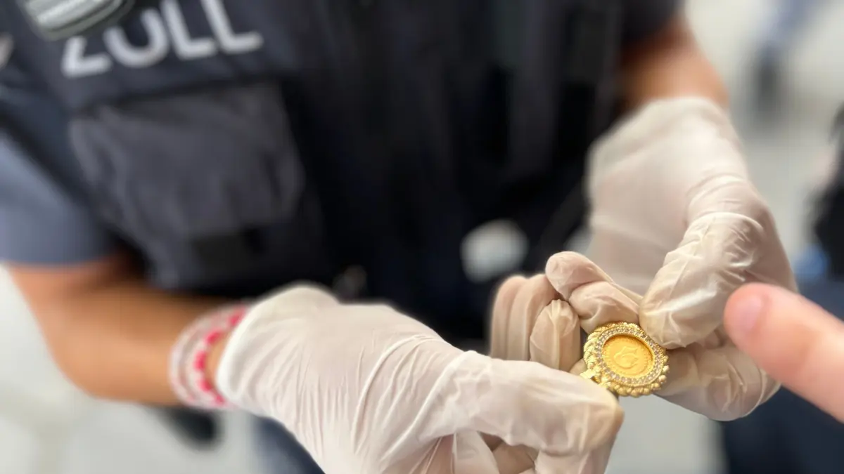 Eine Zollbeamtin zeigt beschlagnahmten Goldschmuck