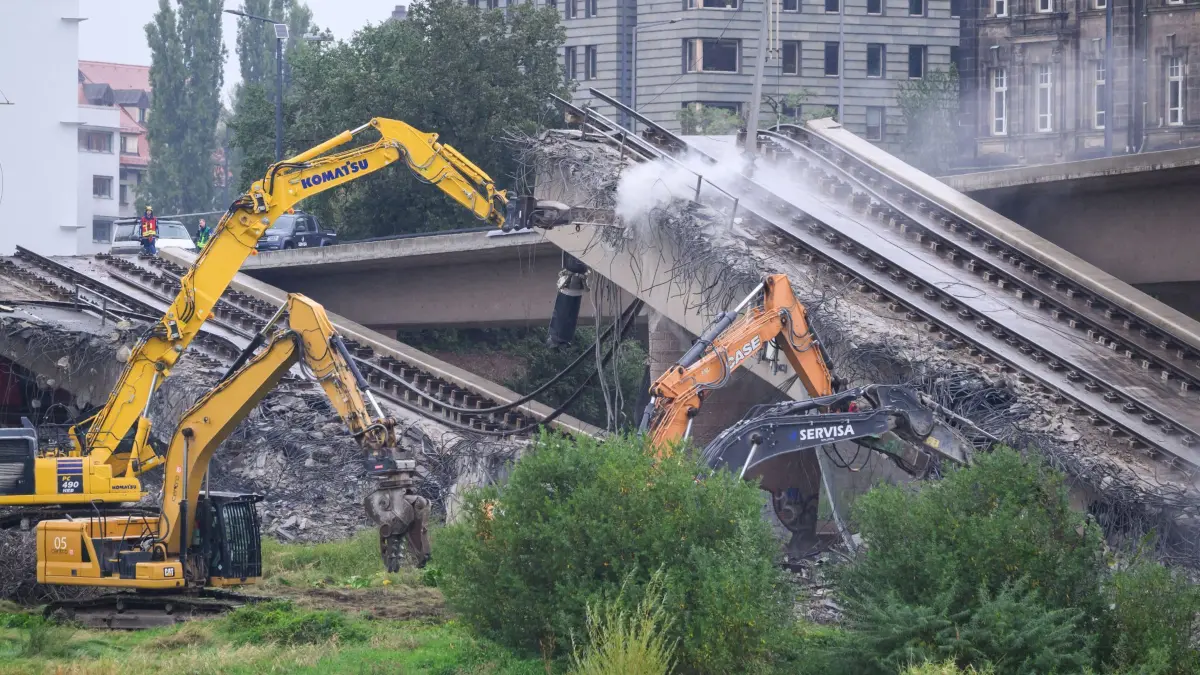 Brückeneinsturz in Dresden: 13.09.2024, Sachsen, Dresden: Mit Baggern werden weitere Teile der eingestürzten Carolabrücke abgerissen. Im Zuge von Abrissarbeiten ist ein weiterer Abschnitt der Carolabrücke in Dresden eingebrochen. Es handelt sich um den Brückenstrang mit Straßenbahngleisen, der in der Nacht zum Mittwoch bereits teilweise in die Elbe gestürzt war. Foto: Robert Michael/dpa +++ dpa-Bildfunk +++