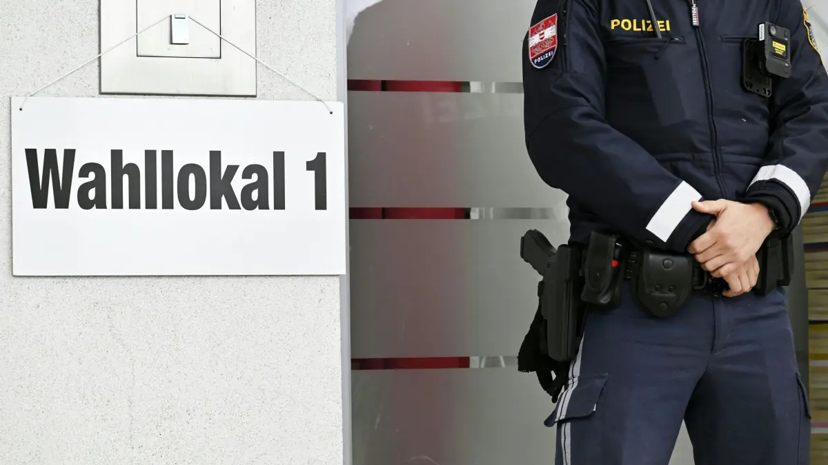 Nationalratswahl in Österreich: 29.09.2024, Österreich, Traiskirchen: Ein Polizist steht neben einem Schild zu einem Wahllokal während der Nationalratswahl. Foto: Hans Klaus Techt/APA/dpa +++ dpa-Bildfunk +++
