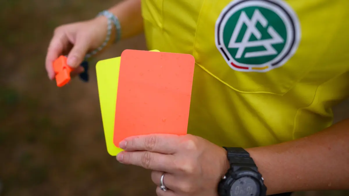 Eine Schiedsrichterin, steht mit roter und gelber Karte auf einem Rasen und hält in der anderen Hand eine Trillerpfeife. 961 Mal kam es zu Spielabbrüchen im Amateurfußball. (zu dpa: «Wegen Gewalt oder Diskriminierung: 961 Amateur-Spiele abgebrochen») +++ dpa-Bildfunk +++