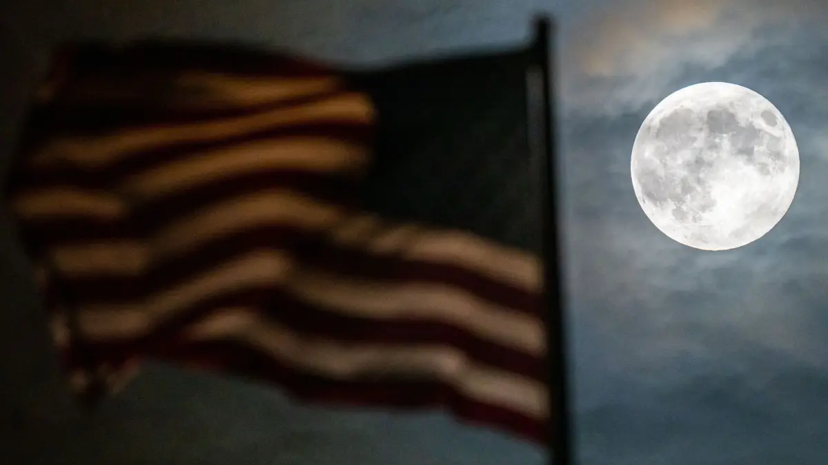 Supermond - Berlin: 17.10.2024, Berlin: Ein besonders groß erscheinender Vollmond, auch Supermond genannt, ist bei leichter Bewölkung hinter der Flagge auf der US-Botschaft zu sehen. Foto: Soeren Stache/dpa +++ dpa-Bildfunk +++