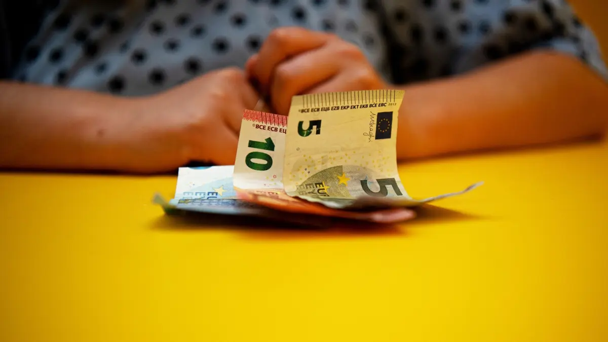 Bargeld liegt vor einer Frau auf einem Tisch: ILLUSTRATION - Damit Ihnen nicht nur ein Teil Ihrer Auszahlung bleibt: P-Konto-Inhaber, die mit Nachzahlungen von Sozialhilfen oder Renten rechnen, sollten rechtzeitig einen Freistellungsantrag dafür stellen. (zu dpa: «Wohngeld, Rente & Co: Vorsicht bei Nachzahlungen auf P-Konto») Foto: Bernd Diekjobst/dpa-mag - Honorarfrei nur für Bezieher des Dienstes dpa-Magazin +++ dpa-Magazin +++