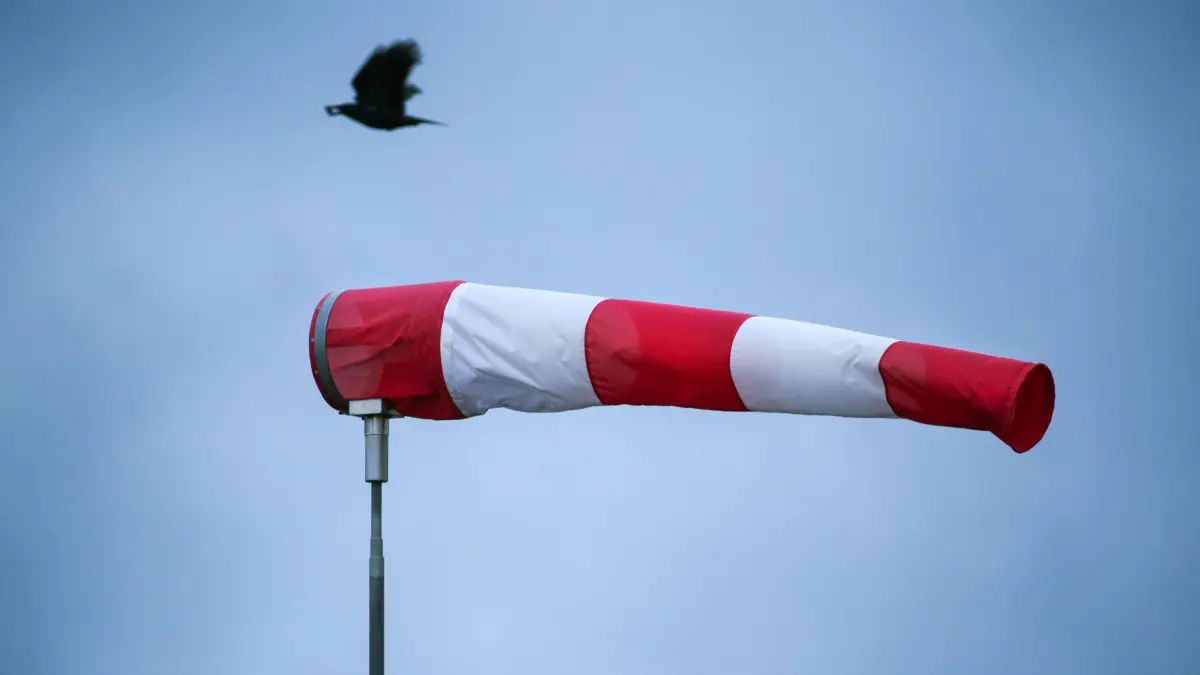 ARCHIV - 22.12.2022, Baden-Württemberg, Riedlingen: Ein Windsack steht im starken Wind, während im Hintergrund eine Krähe fliegt. Für die nächsten Tage bis Heiligabend ist stürmisches Wetter vorhergesagt. (zu dpa: «Sturm und Glätte - Das Wetter für Berlin und Brandenburg») Foto: Thomas Warnack/dpa +++ dpa-Bildfunk +++
