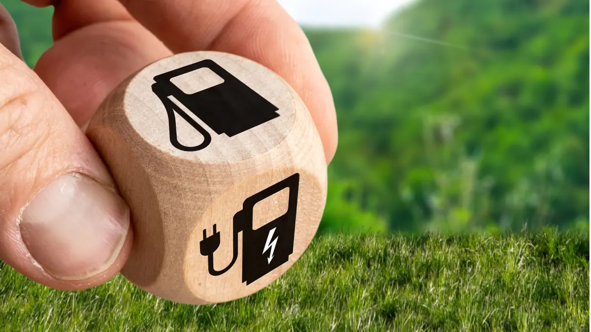 8 June 2023: Wooden cube against nature background with gas pump and e-charging station. Electric mobility concept. Combustion engine vs. e-car PHOTOMONTAGE *** Würfel aus Holz vor Natur Hintergrund mit Zapfsäule und E-Ladestation. Elektro Mobilität Konzept. Verbrenner vs. E-Auto FOTOMONTAGE