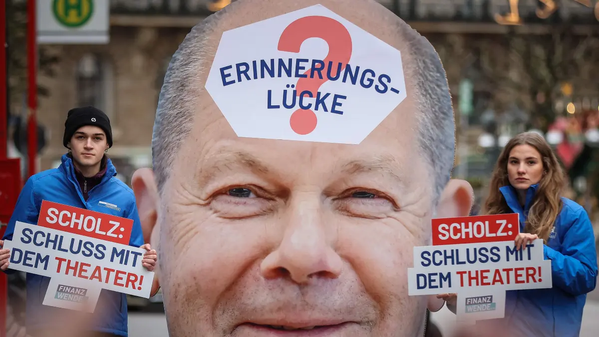 At a protest organised by the association 'Burgerbewegung Finanzwende' (Citizens' movement for a financial turnaround), demonstrators hold placards reading ?Scholz: Stop the theatre!? near a cardboard of a portrait of Federal Chancellor Olaf Scholz reading on his forehead ?Memory Gap?? in Hamburg, northern Germany, on December 6, 2024. A hearing of German Chancellor Olaf Scholz on the "Cum-Ex Affair" at the parliamentary Investigation Committee of the Hamburg Parliament is held on December 6, 2024. (Photo by Ronny HARTMANN / AFP)
