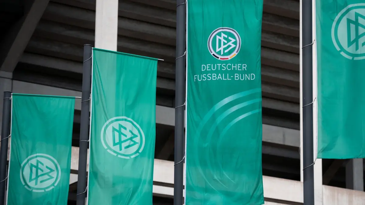 ARCHIV - 28.05.2022, Nordrhein-Westfalen, Köln: Fußball, Frauen: DFB-Pokal, VfL Wolfsburg - Turbine Potsdam, Finale, RheinEnergieStadion. Fahnen mit dem Logo des Deutschen Fussball-Bund (DFB) wehen vor dem Stadion. (zu dpa: «Offiziell: DFB stimmt für Fußball-WM in Saudi-Arabien») Foto: Fabian Strauch/dpa +++ dpa-Bildfunk +++