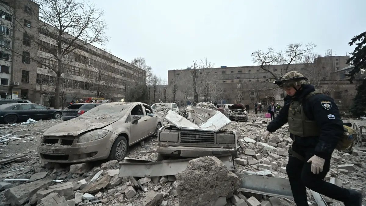 Ukraine-Krieg - Saporischschja: ARCHIV - 10.12.2024, Ukraine, Saporischschja: Ein Polizist geht an Autos vorbei, die nach einem russischen Raketenangriff in Saporischschja im Südosten der Ukraine von den Trümmern zerquetscht wurden. Mindestens drei Menschen sind getötet und 14 Personen verletzt worden. Ein Bürogebäude, ein medizinisches Zentrum und andere Gebäude wurden beschädigt. (zu dpa: «Experte: Bis 150.000 Soldaten für Friedenssicherung in Ukraine nötig») Foto: -/Ukrinform/dpa +++ dpa-Bildfunk +++