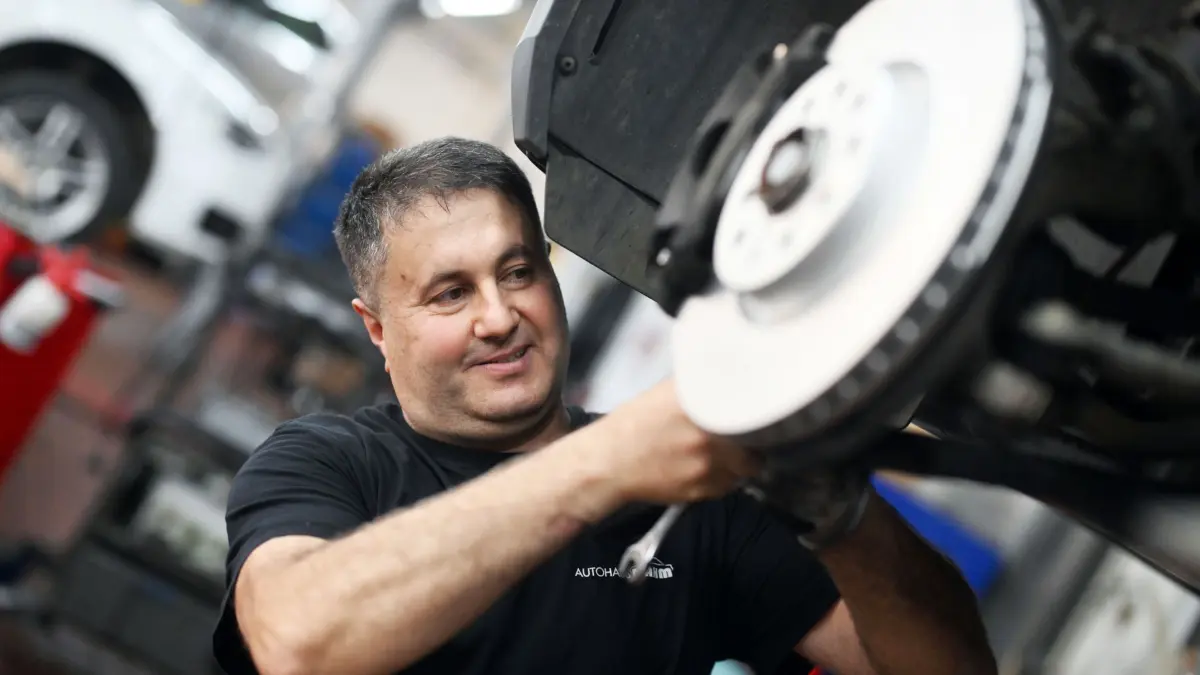 Auszubildender als Kfz-Mechatroniker: PRODUKTION - 27.11.2024, Baden-Württemberg, Kraichtal: Recep Parlak, 52 Jahre alter Auszubildender im dritten Lehrjahr als Kfz-Mechatroniker, wechselt in seinem Ausbildungsbetrieb, einem Autohaus mit Werkstatt, an einem Auto eine Bremsscheibe aus. (zu dpa: ««Ich lerne richtig gerne» - Mit 50 plus in die Lehre gehen») Foto: Uli Deck/dpa +++ dpa-Bildfunk +++