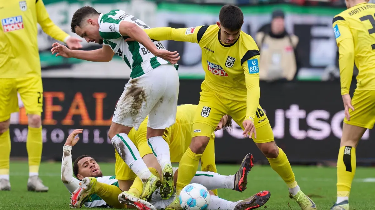 Preußen Münster - SSV Ulm 1846: 21.12.2024, Nordrhein-Westfalen, Münster: Fußball: 2. Bundesliga, Preußen Münster - SSV Ulm 1846, 17. Spieltag, Preußenstadion. Münsters Yassine Bouchama (l) und Aaron Keller von Ulm in Aktion. Unten Etienne Amenyido von Münster. Foto: Bernd Thissen/dpa - WICHTIGER HINWEIS: Gemäß den Vorgaben der DFL Deutsche Fußball Liga bzw. des DFB Deutscher Fußball-Bund ist es untersagt, in dem Stadion und/oder vom Spiel angefertigte Fotoaufnahmen in Form von Sequenzbildern und/oder videoähnlichen Fotostrecken zu verwerten bzw. verwerten zu lassen. +++ dpa-Bildfunk +++
