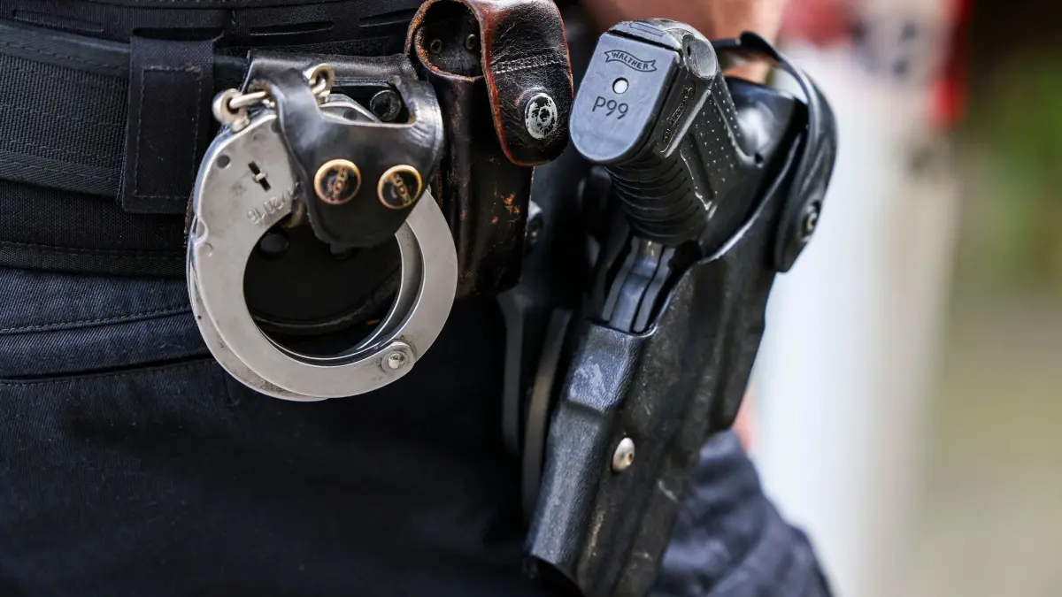 Polizist mit Waffe: ARCHIV - 26.08.2024, Nordrhein-Westfalen, Solingen: Ein Polizeibeamter trägt seine Dienstwaffe Walther P99 und Handschellen bei Suchmaßnahmen in der Nähe der Flüchtlingsunterkunft, in der der mutmaßliche Täter des tödlichen Solinger Messerangriffs gewohnt hat. (zu dpa: «Polizei schießt auf Mann mit Messer») Foto: Christoph Reichwein/dpa +++ dpa-Bildfunk +++