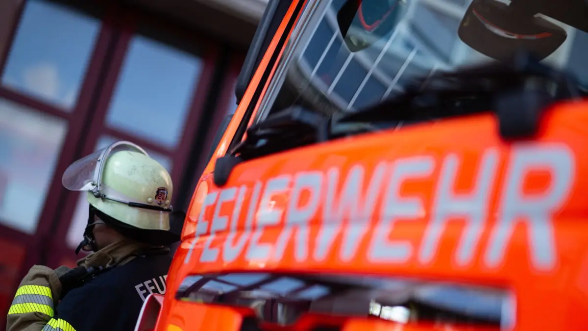 ILLUSTRATION - 08.11.2023, Baden-Württemberg, Stuttgart: Eine Einsatzkraft der Feuerwehr steht neben einem Einsatzfahrzeug der Feuerwehr. (zu dpa: «Sechsstelliger Schaden nach Brand in Geislingen») Foto: Marijan Murat/dpa +++ dpa-Bildfunk +++