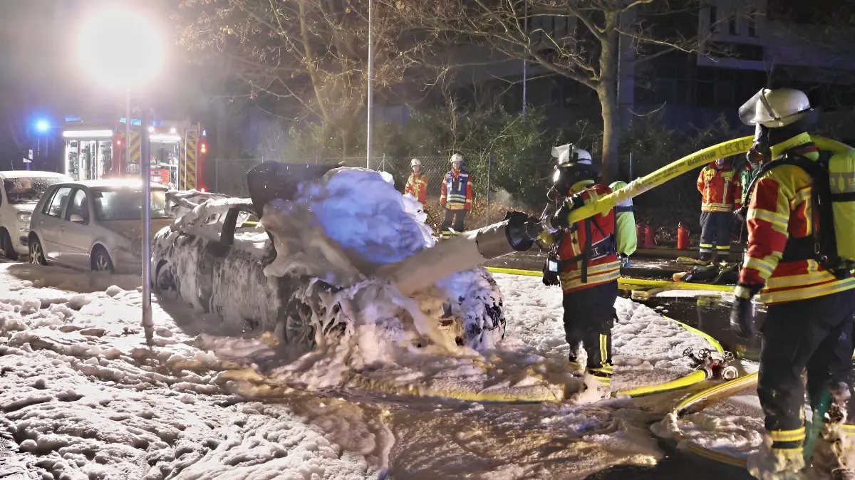 10.01.2025: Am frühen Morgen des 10.1.2025 wurde die Freiwillige Feuerwehr Kornwestheim gegen 3:10 Uhr mit dem Alarmstichwort B3 in die Kreidlerstraße alarmiert. Noch während der Anfahrt wurde auf Grund der Anrufe das Alarmstichwort auf B4 erhöht. Beim Eintreffen der ersten Fahrzeuge stand ein hochmotorisierter Audi S5 Sportsback im Vollbrand, ein dahinter stehender Pkw und ein Wohngebäude waren von Flammen und Rauch bedroht. Umgehend wurden ein Löschrohr mit Wasser und ein weiteres Rohr mit einer Schaumpistole vorgenommen. Da der Benzintank aufgemantelt war wurden zudem Pulverlöscher und ein Mittelschaumrohr eingesetzt, da sich der auslaufende Kraftstoff immer wieder entzündete. Weiterhin wurden Sperren errichtet, um zu verhindern, dass das Gemisch in die Kanalisation fließt. Gegen 4:30 Uhr konnten die letzten Einsatzfahrzeuge wieder einrücken. Von der Polizei waren starke Kräfte der Schutz- und Kriminalpolizei vor Ort, auch der Polizeihubschrauber schwebte über der Einsatzstelle.
Foto: KS-Images.de/Andreas Rometsch