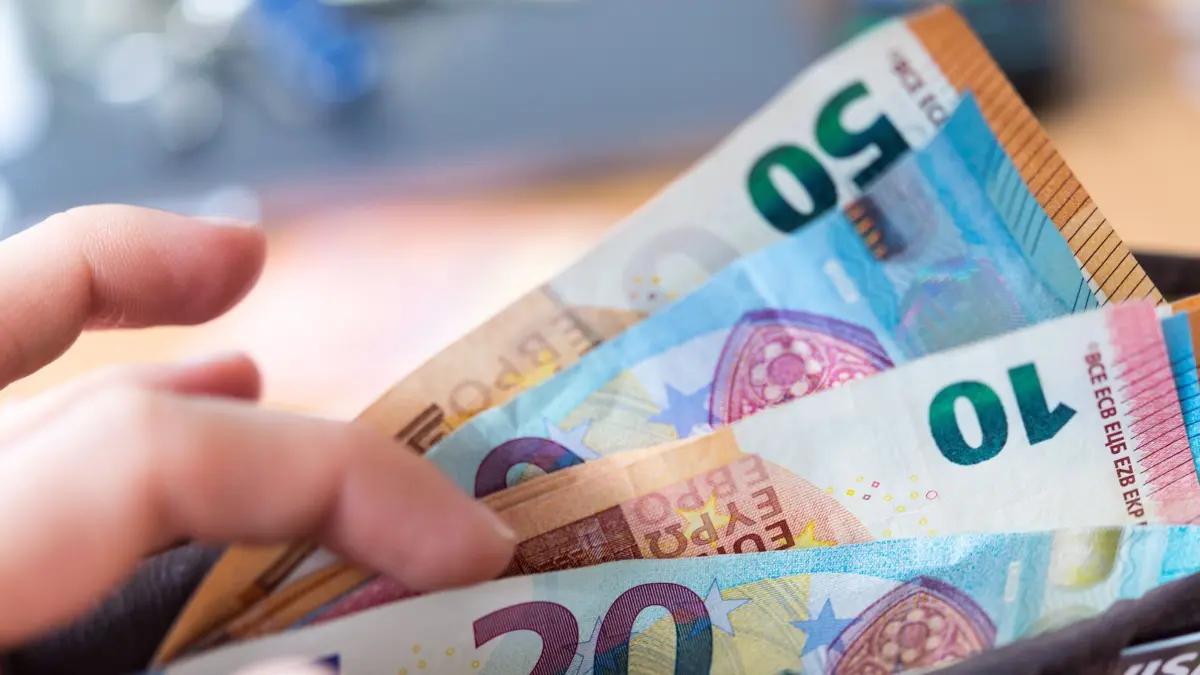 Eine Frau hält ein Portemonnaie in der Hand, in dem Geldscheine stecken. Die Caritas und die Deutsche Bank bescheren ihre Beschäftigten mit einem steuerfreien Zuschuss als Inflationsausgleich, ebenso wie viele weitere Arbeitgeber.(zu dpa «Extra-Geld vom Chef als Inflationsausgleich») +++ dpa-Bildfunk +++