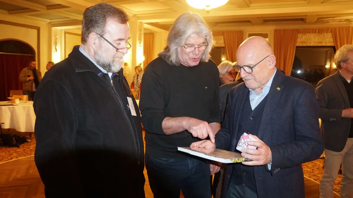 Bernd Leix (links) von den Denkmalfreunden Waldlust überreicht Minister Winfried Hermann (rechts) ein Buch über die Waldlust. In der Mitte Siegfried Kögel vom F23, der Hermann aus seiner Zeit in Stuttgart kennt.