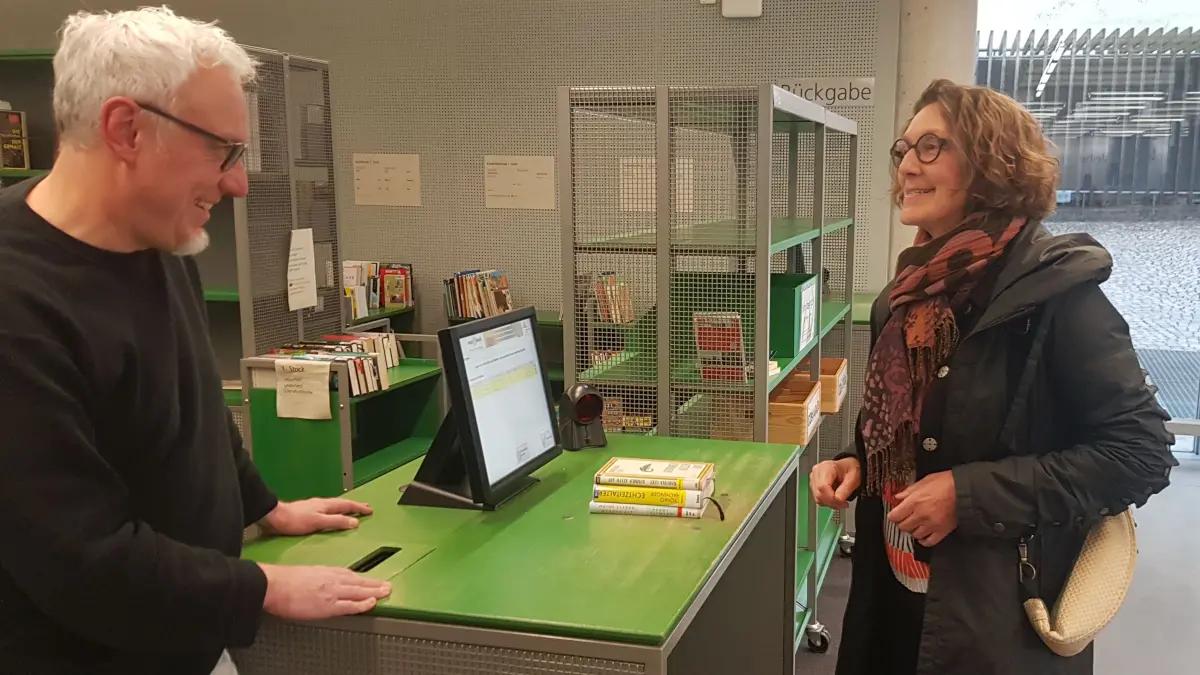 Bürgermeisterin Iris Mann gibt Bücher in der Zentralbibliothek zurück. Das und vieles mehr ist künftig auch an Samstagnachmittagen möglich. Links im Bild: Bibliotheksleiter Martin Szlatki.