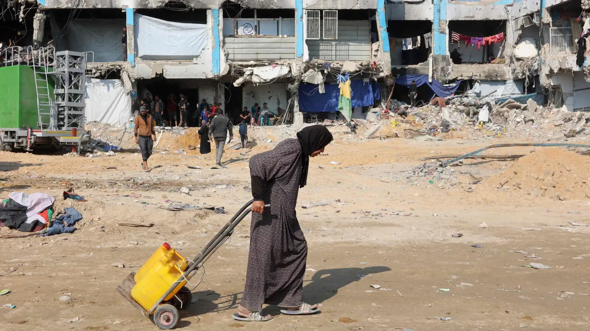 A Palestinian woman pulls a trolley with water cans in Jabalia in the northern Gaza Strip on February 4, 2025. (Photo by Omar AL-QATTAA / AFP)