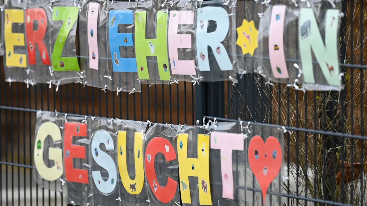 Kita-Personal gesucht: ILLUSTRATION - 10.02.2023, Hessen, Frankfurt/Main: Mit bunten Buchstaben sind die Worte „Erzieher*in gesucht“ geformt, die an einem Zaun einer Kindertagesstätte im Stadtteil Sachsenhausen befestigt sind. (zu dpa: «Kommunen äußern sich zur Kinderbetreuung») Foto: Arne Dedert/dpa +++ dpa-Bildfunk +++