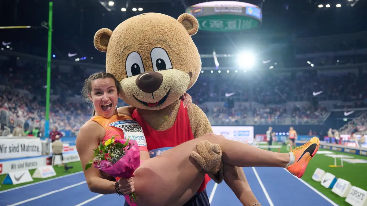 Leichtathletik Meeting Düsseldorf: 09.02.2025, Nordrhein-Westfalen, Düsseldorf: Leichtathletik/Halle, Meeting: Rosina Schneider aus Deutschland freut sich nach ihrem Sieg im Finale über 60 Meter Hürden der Frauen und wird von Maskottchen Berlino getragen. Foto: Bernd Thissen/dpa +++ dpa-Bildfunk +++