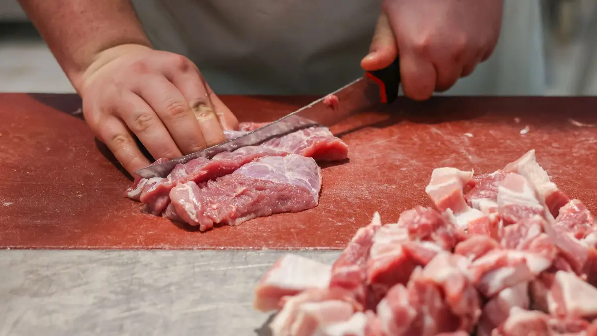 Handwerksforum Ost: 12.02.2025, Sachsen, Leipzig: Ein junger Metzger schneidet Schweinefleisch am Stand einer Schaumetzgerei auf der Messe «Handwerk live». Am gleichen Tag findet hier das Handwerksforum Ost zum Thema «Nachwuchs- und Fachkräftemangel im Handwerk - Was ist zu tun?» statt. Foto: Jan Woitas/dpa +++ dpa-Bildfunk +++
