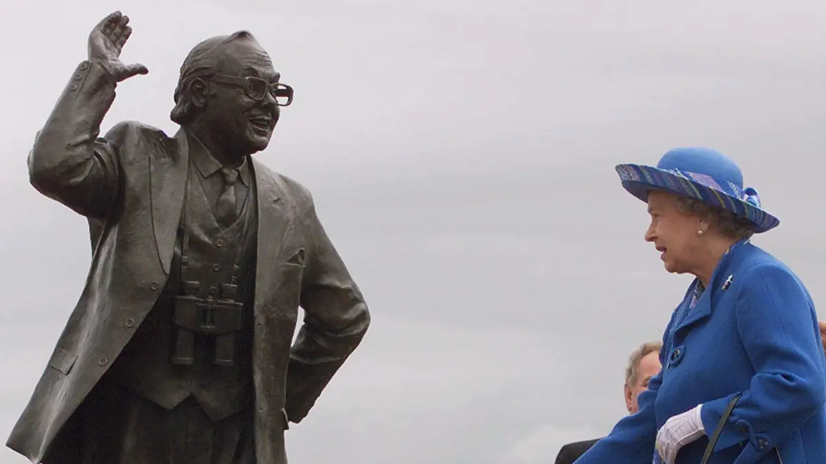Queen Elizabeth II. hat 1999 eine Statue für Eric Morecambe enthüllt. Der Comedian, dessen Brille Robbie Williams jetzt hat.