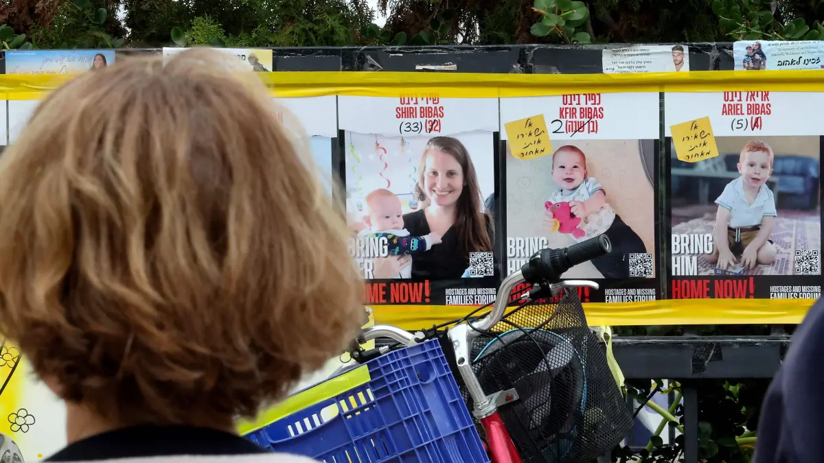 A woman stares at posters of Shiri Bibas and her two young sons, Kfir and Ariel outside the Tel Aviv Museum of Art, now informally called the "Hostages Square", on February 19, 2025. Hamas agreed on February 18 to return the bodies of eight dead hostages in two groups this week and next, including the remains of Shiri Bibas and her two young sons, Kfir and Ariel, who have become national symbols in Israel of the hostages' ordeal. (Photo by Jack GUEZ / AFP)