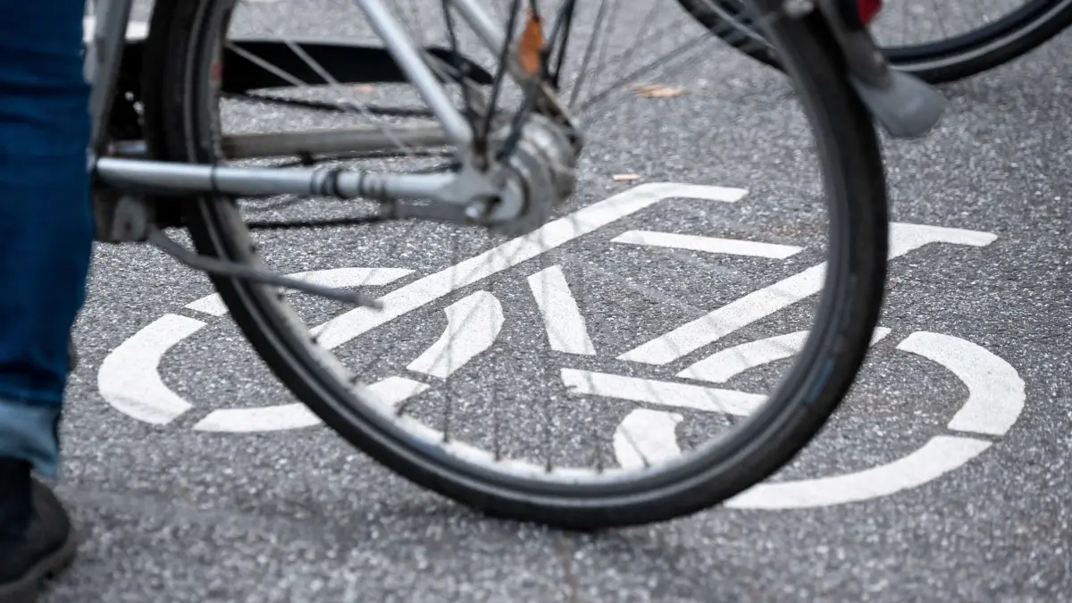 ARCHIV - 31.10.2021, Hamburg: Ein Fahrrad-Symbol ist auf der Fahrbahn einer Straße hinter einem Fahrrad zu sehen. (zu dpa: «2,3 Millionen Euro für Geh- und Radweg in Rüdesheim») Foto: Jonas Walzberg/dpa +++ dpa-Bildfunk +++