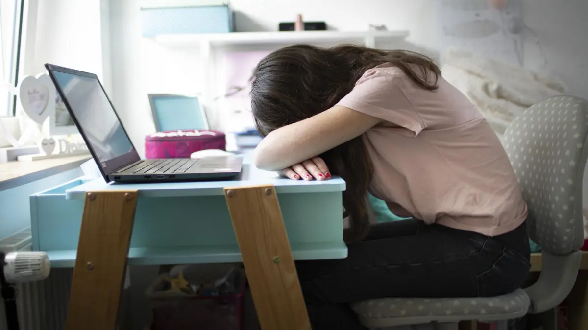 Jugendliche leiden unter Folgen der Corona-Kontaktbeschraenkungen: Maedchen traurig und alleine an ihrem Schreibtisch (Symbolfoto vom 16.04.2021). Einsam, enttaeuscht, depressiv, dick: Schulschliessungen und Kontaktbeschraenkungen waehrend der Pandemie haben bei vielen Jungen und Maedchen Folgen hinterlassen. Aerzte und Kinderschutzbund mahnen Therapieplaetze und eine politische Reaktion an. Eine Analyse des Bundesinstituts fuer Bevoelkerungsforschung aus dem vergangenen Jahr haelt fest, dass die Kita- und Schulschliessungen in Deutschland im Schnitt 183 Tage dauerten und zu einem "Anstieg der Angstsymptome und Depressionen bei Kindern und Jugendlichen, begleitet von einem deutlichen Rueckgang der koerperlichen Aktivitaet und Fitness" gefuehrt haben. (Siehe epd-Feature vom 03.03.2025) *** Local Caption *** 00497704