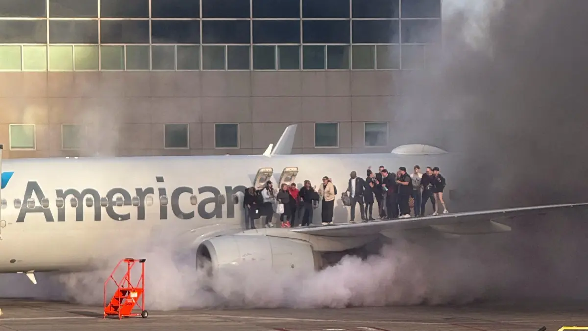 This image courtesy of Branden Williams shows passengers standing on the wing of an American Airlines plane as they are evacuated after it caught fire while at a gate at Denver International Airport in Denver, Colorado, March 13, 2025. (Photo by Branden Williams / Courtesy of Branden Williams / AFP) / RESTRICTED TO EDITORIAL USE - MANDATORY CREDIT "AFP PHOTO / HANDOUT / Branden WILLIAMS " - NO MARKETING NO ADVERTISING CAMPAIGNS - DISTRIBUTED AS A SERVICE TO CLIENTS