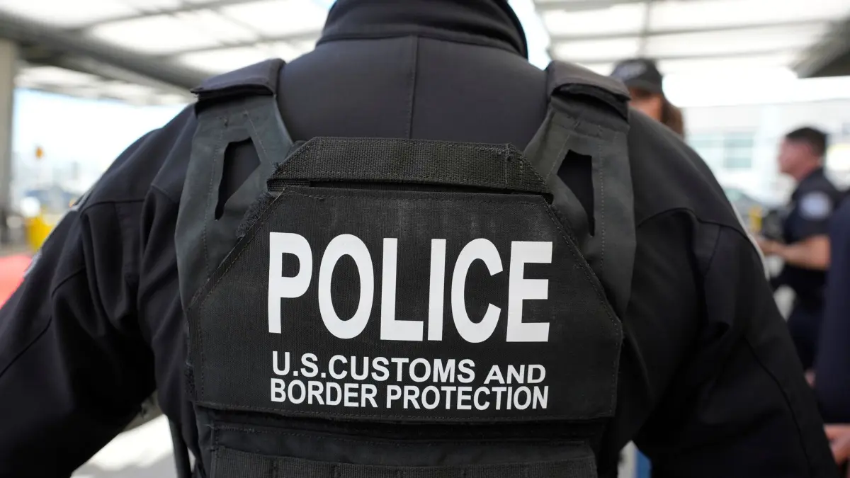 US-Heimatschutzministerin Noem: 16.03.2025, USA, San Diego: Ein Beamter der Zoll- und Grenzschutzbehörde beobachtet, wie die US-Heimatschutzministerin Noem durch den San Ysidro Port of Entry geht. Foto: Alex Brandon/AP/dpa +++ dpa-Bildfunk +++