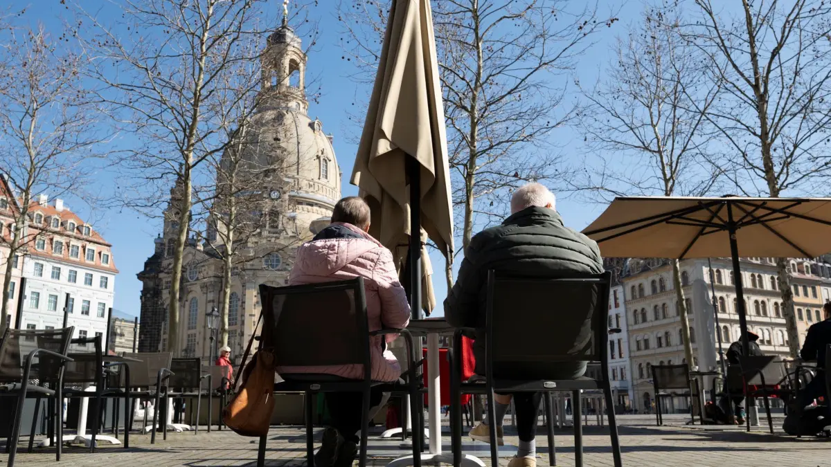 Kalendarischer Frühlingsanfang - Dresden: 20.03.2025, Sachsen, Dresden: Passanten sitzen in der Frühlingssonne auf dem Neumarkt vor der Frauenkirche in einem Cafe. Foto: Sebastian Kahnert/dpa +++ dpa-Bildfunk +++