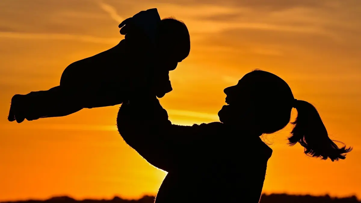 Weltglücksbericht: ARCHIV - 09.10.2022, Brandenburg, Sieversdorf: Eine Mutter mit ihrem acht Monate alten Baby sind im Sonnenuntergang auf einem Feldweg zu sehen. (zu dpa: «Finnen bleiben die Glücklichsten - Deutschland auf Platz 22») Foto: Patrick Pleul/dpa +++ dpa-Bildfunk +++