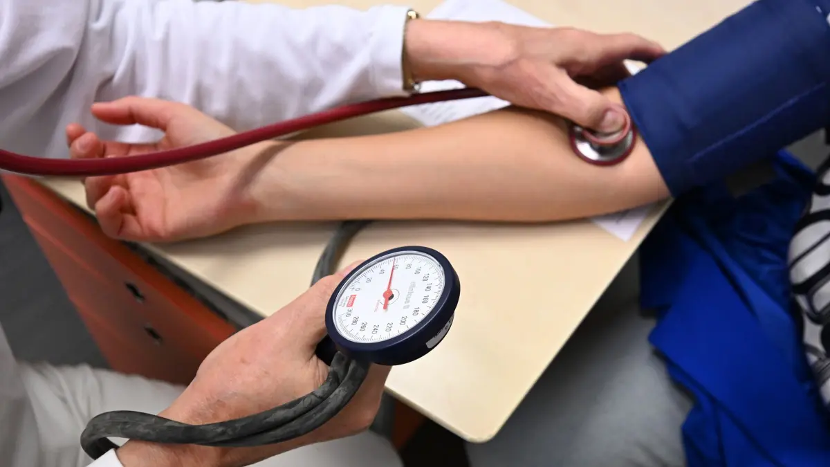 Ärztliche Bereitschaftspraxis: SYMBOLBILD - 16.10.2024, Baden-Württemberg, Leonberg: Ein Arzt misst in einer Bereitschaftspraxis in einem Krankenhaus in einem Untersuchungsraum bei einer Patientin den Blutdruck (gestellte Szene). (zu dpa: «Im Vergleich: viele Ärztinnen in Thüringer Arztpraxen») Foto: Bernd Weißbrod/dpa +++ dpa-Bildfunk +++