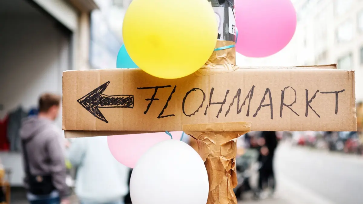 Handgeschriebenes Schild mit der Aufschrift Flohmarkt Ein handgeschriebenes Schild auf Pappkarton mit der Aufschrift Flohmarkt an einem Laternenpfahl mit Luftballons in einer städtischen Umgebung Copyright: xZoonar.com/GerdxHarderx 21049609